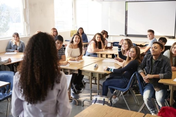 Teacher engaging with students in a lively classroom setting, fostering learning and discussion.