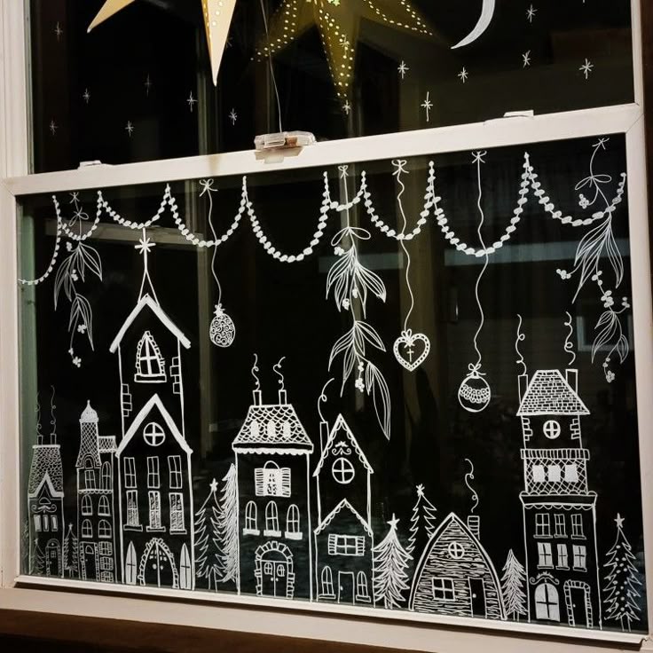 Festive window art with whimsical houses, stars, and hanging ornaments on a dark background, reflecting holiday cheer.
