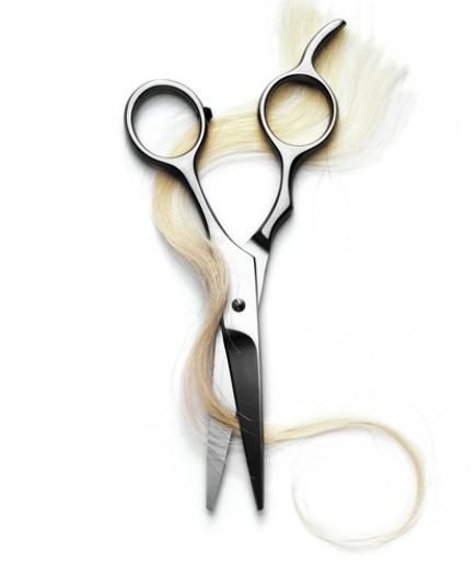 Hair scissors cutting blond strands on white background.