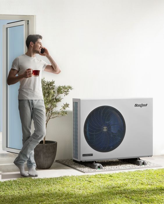 Man enjoying coffee on phone near home heating unit.