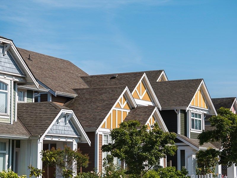 Colorful suburban houses with pitched roofs under a clear blue sky.
