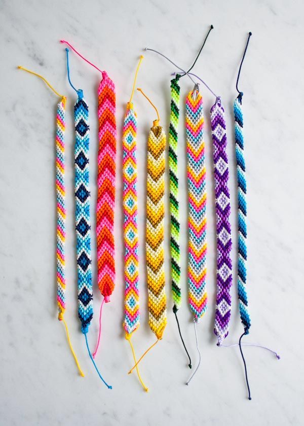 Colorful handmade friendship bracelets arranged on a white background.