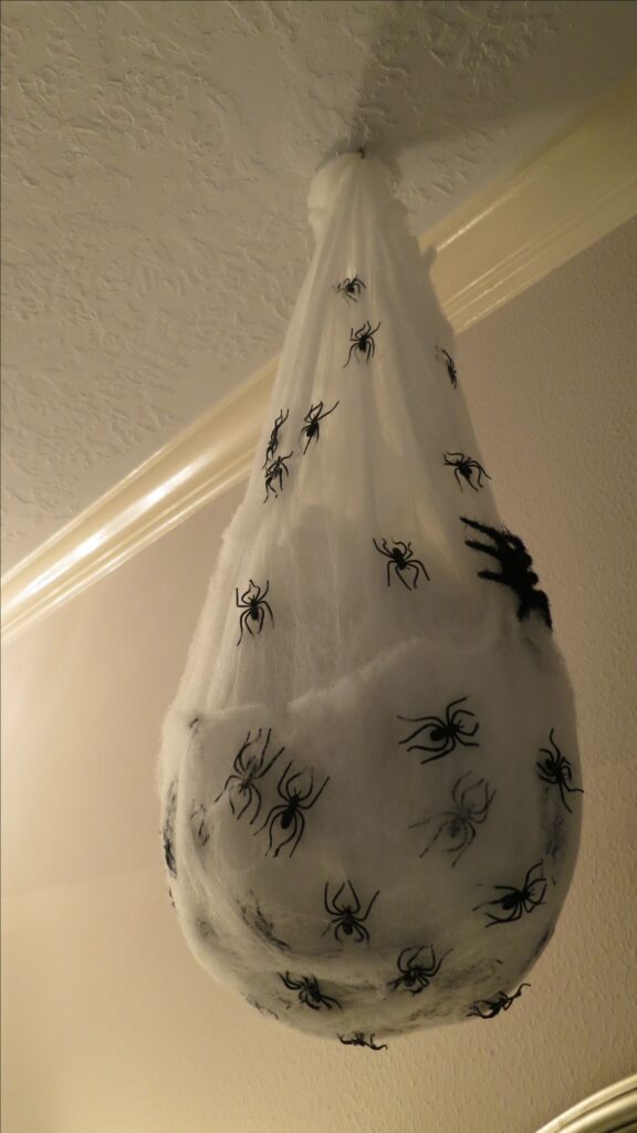 b11a7411ba2c95796bf05c4e173608cf Hanging Halloween decoration with fake spiders on white webbing, attached to ceiling corner for spooky ambiance. | Sky Rye Design Hanging Halloween decoration with fake spiders on white webbing, attached to ceiling corner for spooky ambiance.