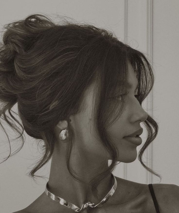 Elegant woman in profile with updo hairstyle, large earrings, and a stylish necklace, set in black-and-white.