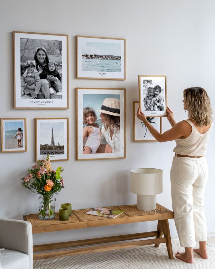 b75b01a6f1d234d832075bb68bf3ab05 Woman arranging framed family photos on a wall; cozy home decor with memories displayed creatively. | Sky Rye Design Woman arranging framed family photos on a wall; cozy home decor with memories displayed creatively.