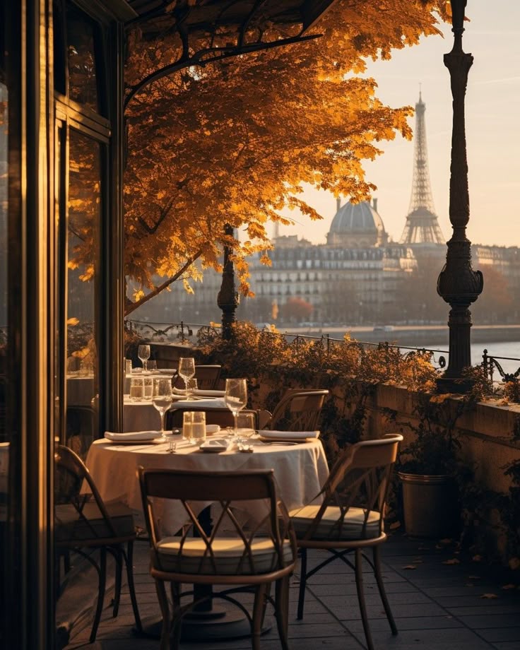 Cozy Parisian terrace café with autumn leaves, set table, Eiffel Tower view, warm sunset glow.
