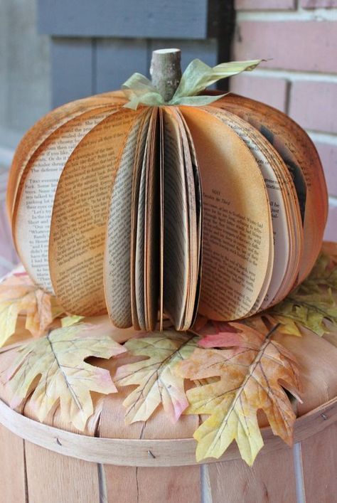 Creative pumpkin made from book pages on a wooden surface with autumn leaves, perfect fall decor idea.