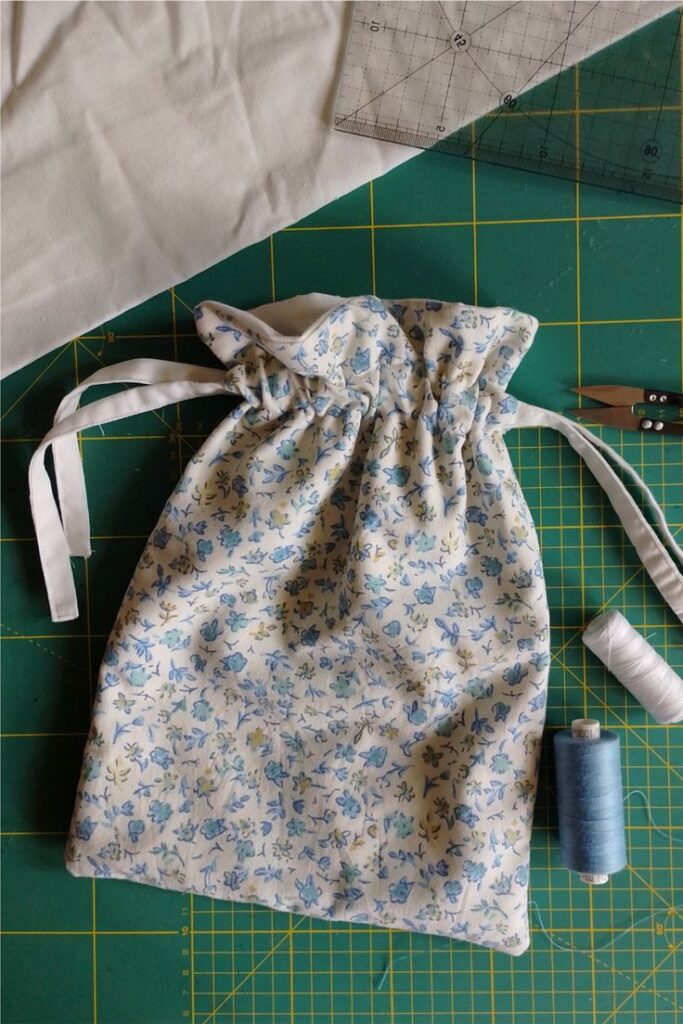 Floral drawstring bag on sewing table with tools and threads, ideal for DIY craft projects and fabric enthusiasts.