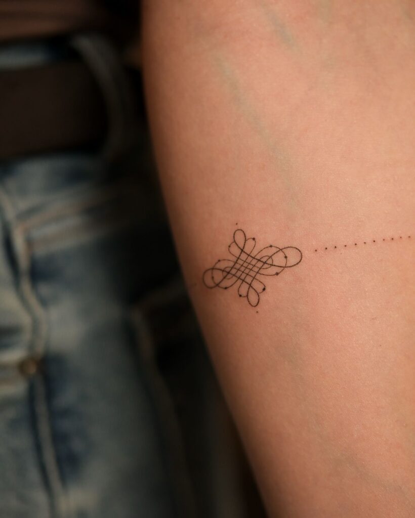 Minimalist geometric tattoo on forearm with intricate line art, close-up.
