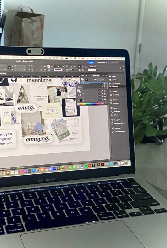 Laptop displaying Adobe InDesign project with various design elements on screen.