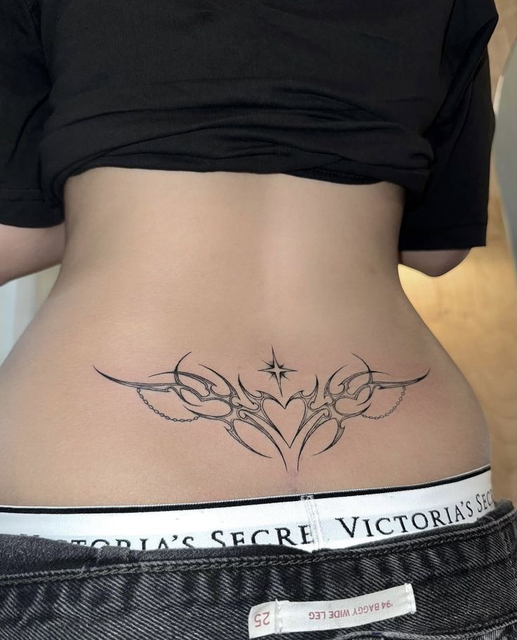 Lower back tribal tattoo with heart and star design above jeans waistband.