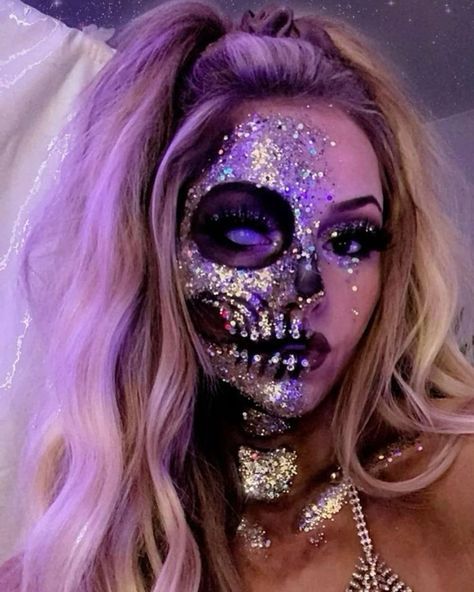 Woman with glittery skull makeup under purple lighting, showcasing creative Halloween costume.