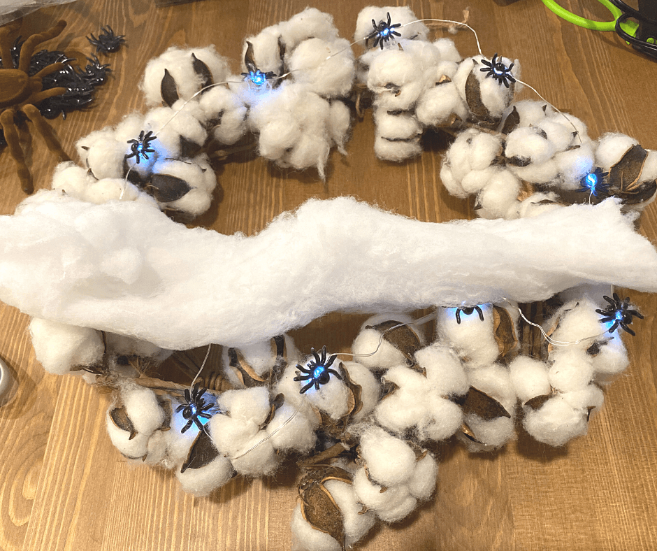 cotton-spider-web-wreath-web1 Cotton wreath with blue LED lights and spider decorations on a wooden table. | Sky Rye Design Cotton wreath with blue LED lights and spider decorations on a wooden table.