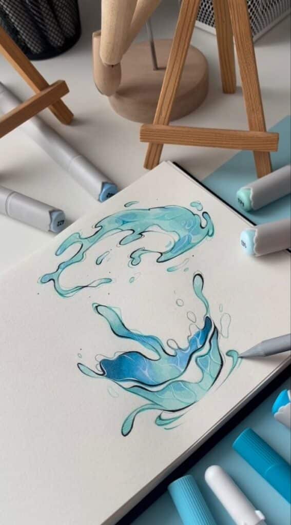 Artistic watercolor splash drawing on sketchbook near markers and wooden easel on desk.