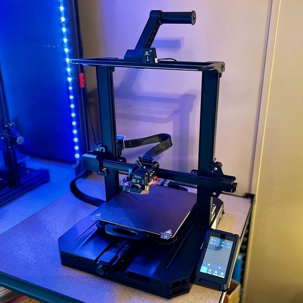 Modern desktop 3D printer with touch screen interface on a table, ready for printing projects.