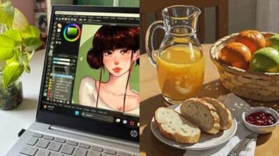Digital art on laptop beside breakfast table with juice, bread, and fruits.