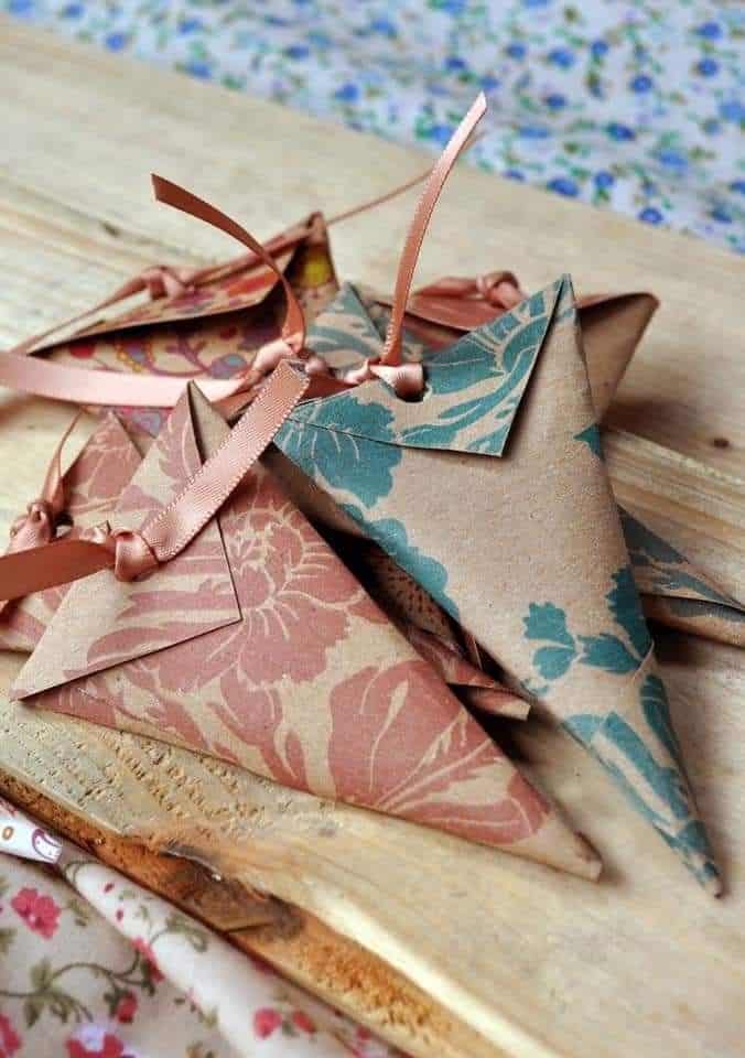 Decorative paper gift pouches with floral patterns and ribbons on a wooden surface.