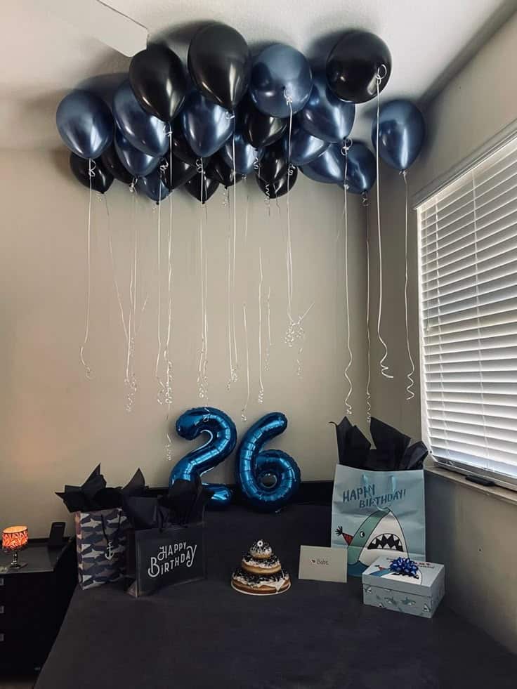 Birthday celebration with blue and black balloons, gifts, and '26' balloon display in a cozy room.