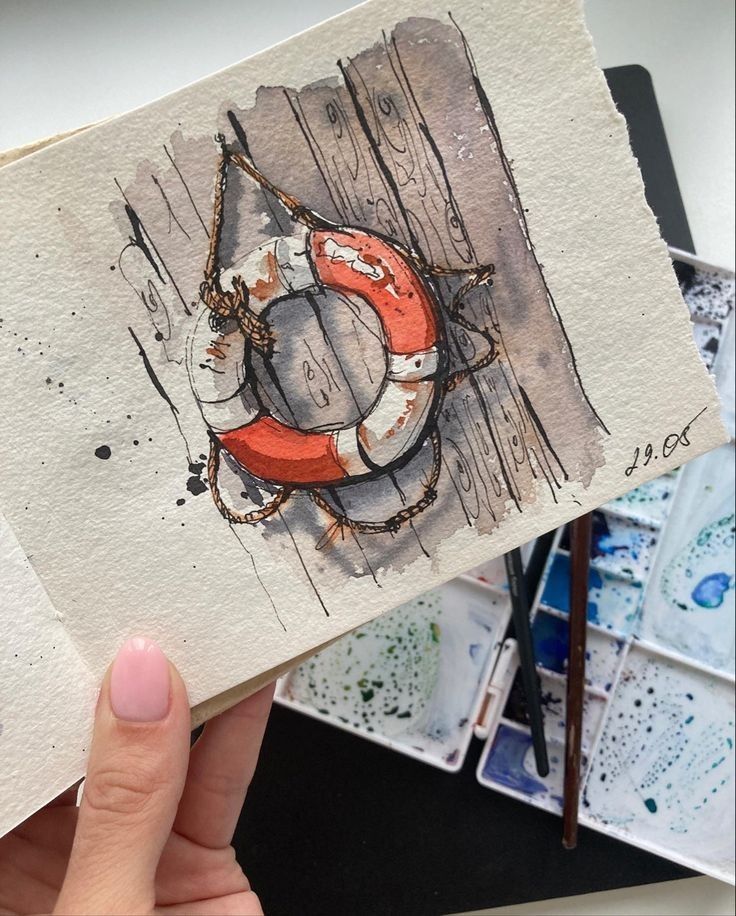 Watercolor sketch of a lifebuoy on wood, held above a paint palette with brushes, signed 29.08.
