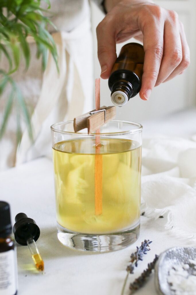 ec6d7bb6b32b540f08211982d303f43f Hand pouring essential oil into a DIY candle with a wooden wick and clothespin holder. | Sky Rye Design Hand pouring essential oil into a DIY candle with a wooden wick and clothespin holder.