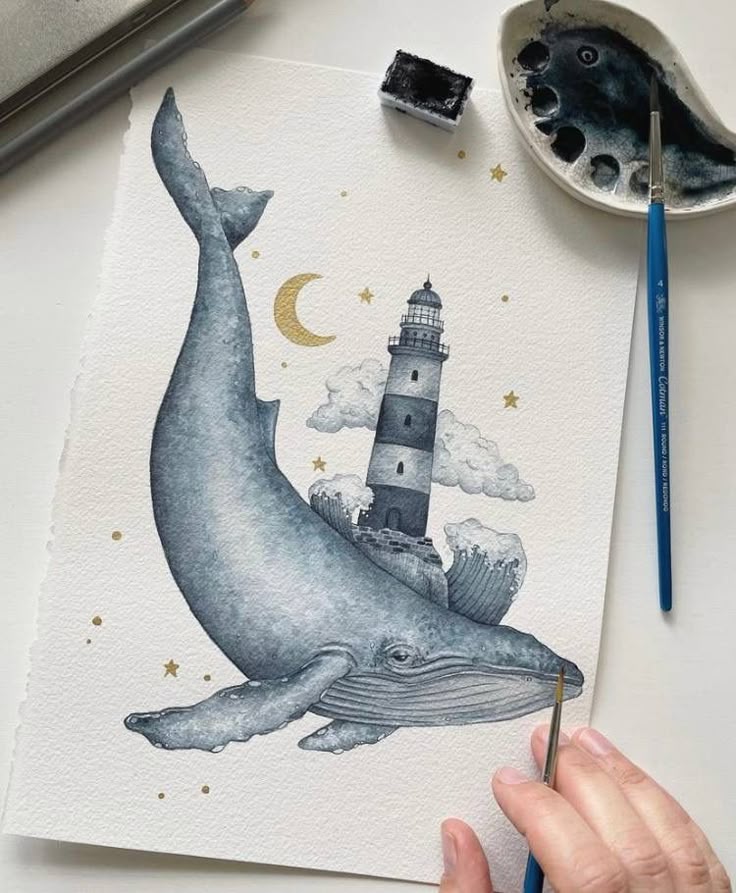 Whale and lighthouse watercolor painting with stars and crescent moon, artist's hand holding a brush.