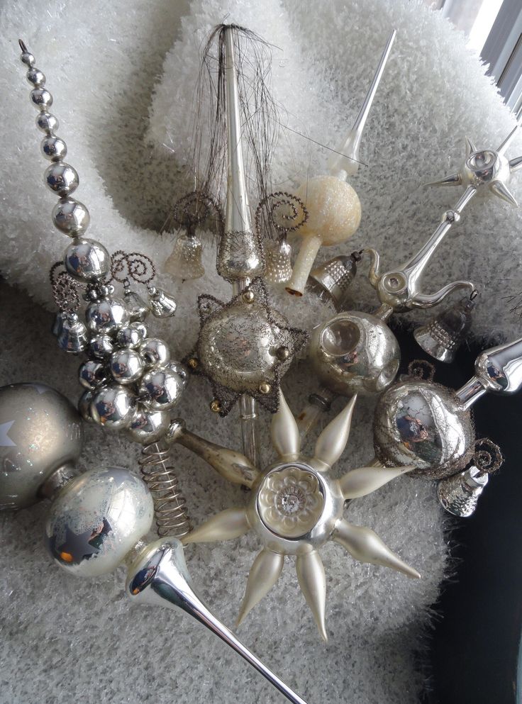 Silver and glass Christmas tree toppers with intricate designs on a textured white background. Festive holiday decor.