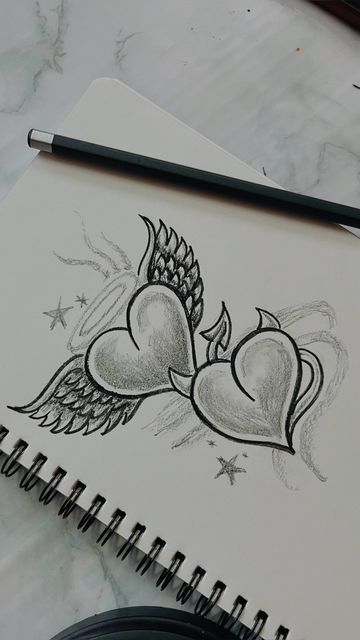 Pencil sketch of two hearts with wings and stars on a notebook page, emphasizing creativity and love-themed art.