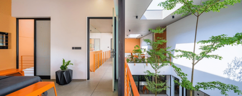 Modern indoor balcony view with orange accents and potted plants in a bright, minimalistic space.
