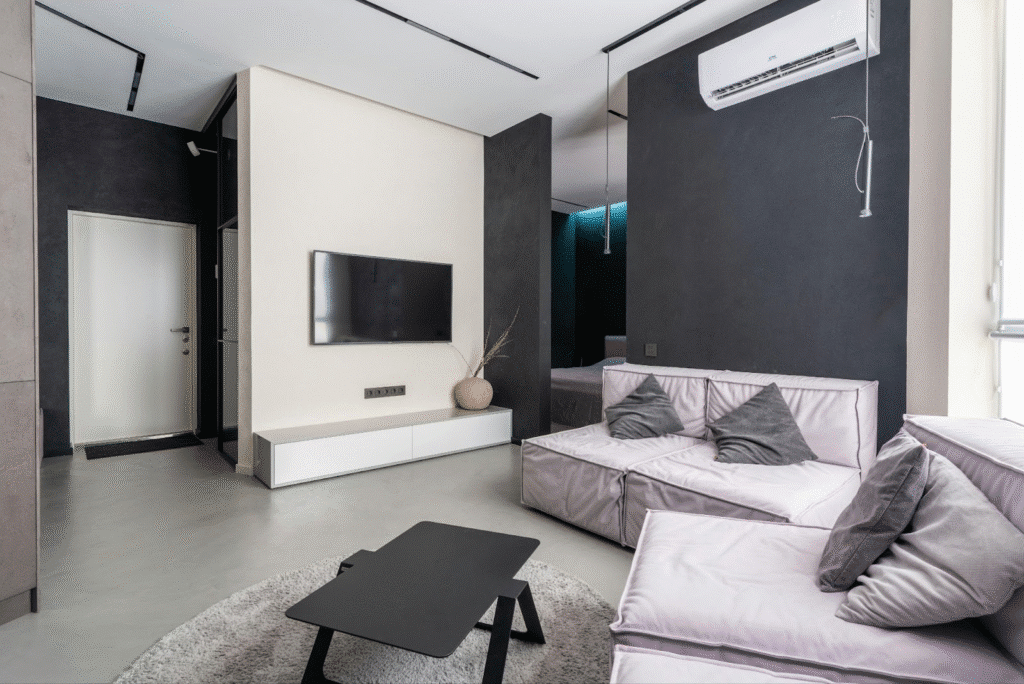 image Modern minimalist living room with black accents, gray couches, wall-mounted TV, and sleek furniture. | Sky Rye Design Modern minimalist living room with black accents, gray couches, wall-mounted TV, and sleek furniture.