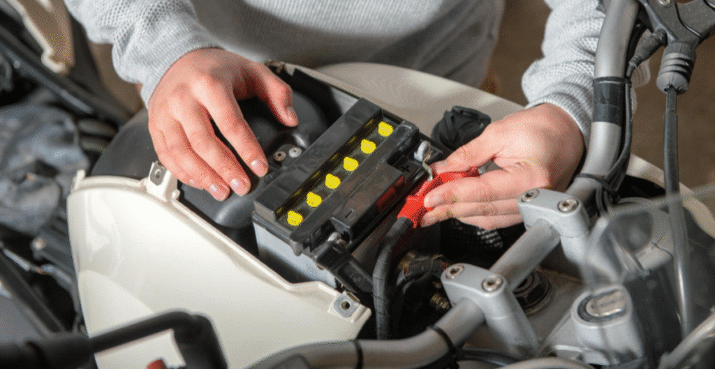 image Person installing a new battery in a motorcycle, focusing on hands and components. | Sky Rye Design Person installing a new battery in a motorcycle, focusing on hands and components.