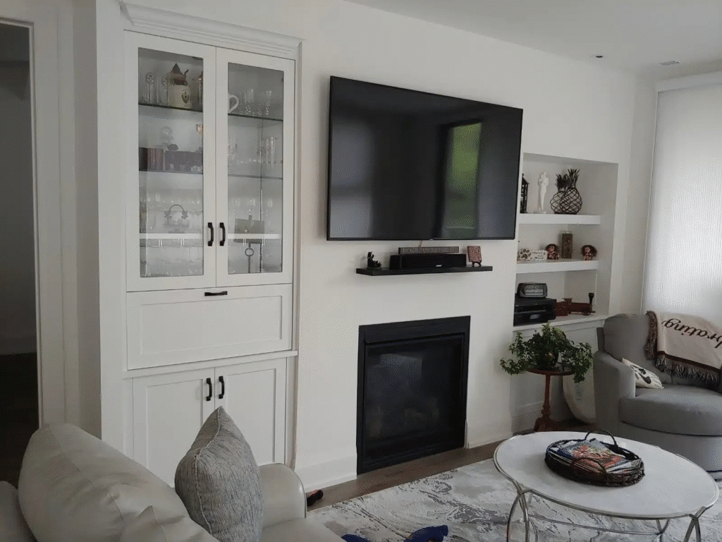 image Modern living room with large TV, fireplace, white cabinet, and cozy seating area. | Sky Rye Design Modern living room with large TV, fireplace, white cabinet, and cozy seating area.