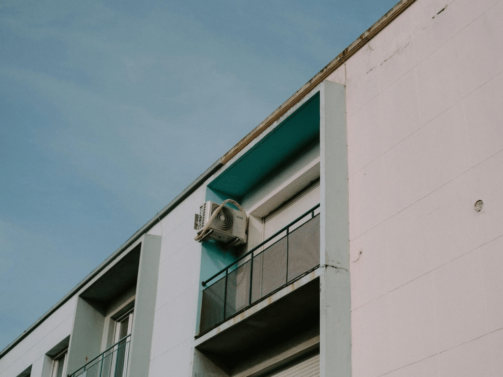 Modern apartment exterior with air conditioning unit and blue sky background.