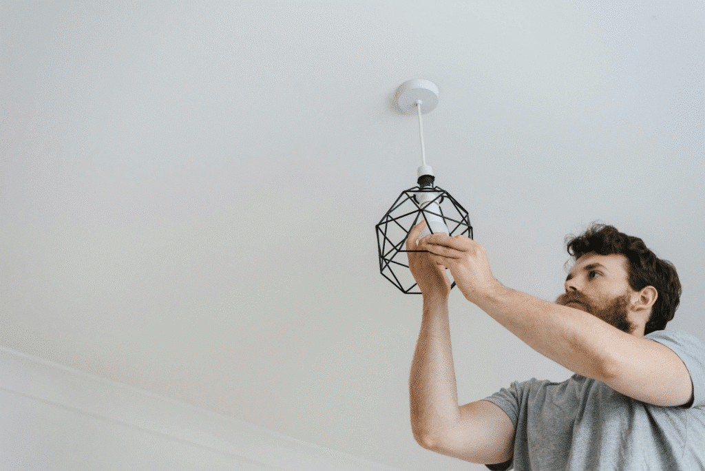 Man installing a modern light fixture on ceiling, focusing on home improvement and DIY lighting projects.