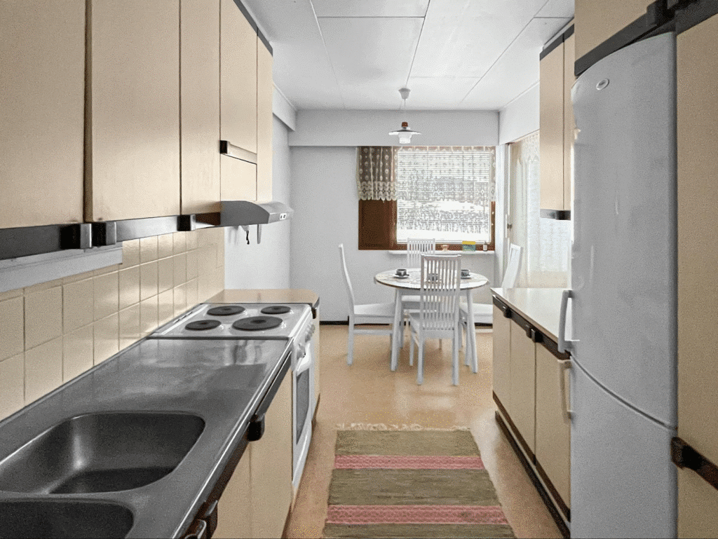 Retro kitchen with beige cabinets, electric stove, and cozy dining area by the window.
