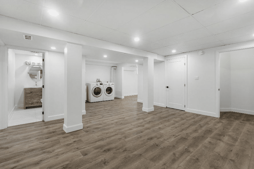 Spacious modern basement with hardwood floors, recessed lighting, laundry area, and a bathroom.