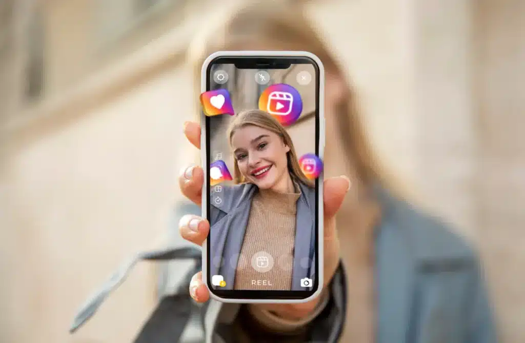 Woman holding smartphone with social media app interface, showcasing profile features such as likes and reels.
