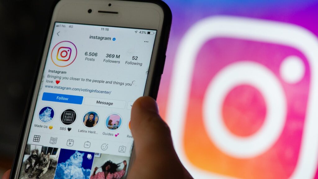 Close-up of a smartphone displaying an Instagram profile, with the Instagram logo blurred in the background.