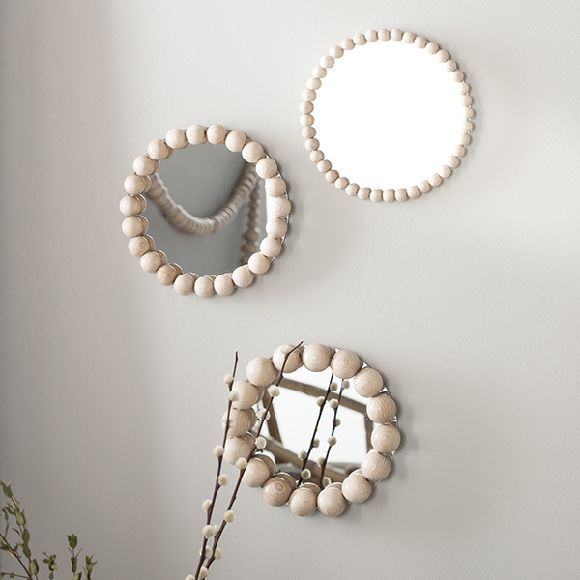 Three round mirrors with wooden bead frames on a wall, adding a stylish and modern touch to home decor.