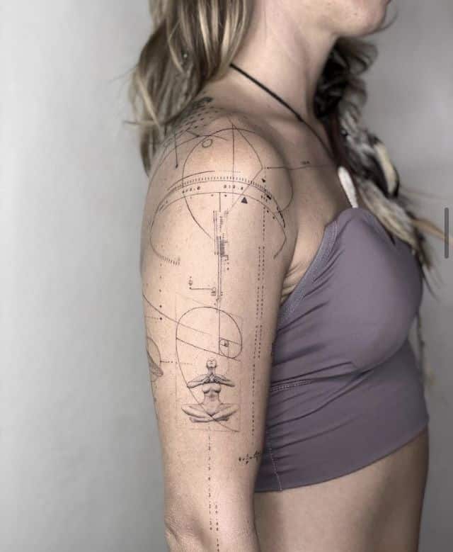 Geometric tattoo with meditative figure on woman's arm, wearing a purple top, side view.