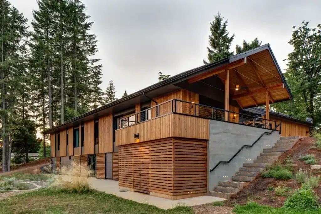 pumpkin-ridge-passive-house-07 Modern wooden house with large deck and stairs surrounded by tall trees, showcasing contemporary architecture design. | Sky Rye Design Modern wooden house with large deck and stairs surrounded by tall trees, showcasing contemporary architecture design.