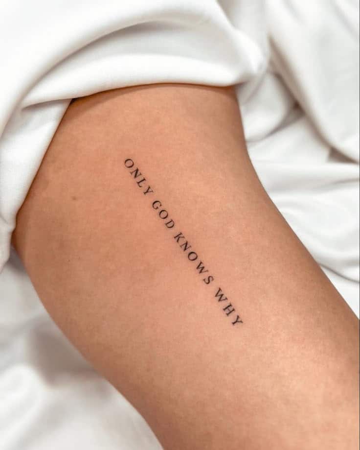 Arm tattoo with the words ONLY GOD KNOWS WHY on skin, surrounded by white fabric, minimalist style.