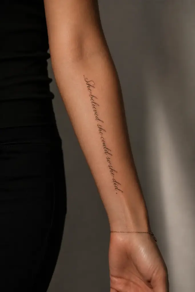 4ae2477e-9c18-4a9f-921c-db0f941e8e47 Minimalist script forearm tattoo reading 'She believed she could so she did' on woman's inner arm with dainty bracelet | Sky Rye Design Minimalist script forearm tattoo reading'She believed she could so she did' on woman's inner arm with dainty bracelet