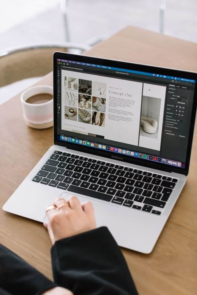 Person working on design project on a laptop with a cup of coffee on a wooden desk. Web design