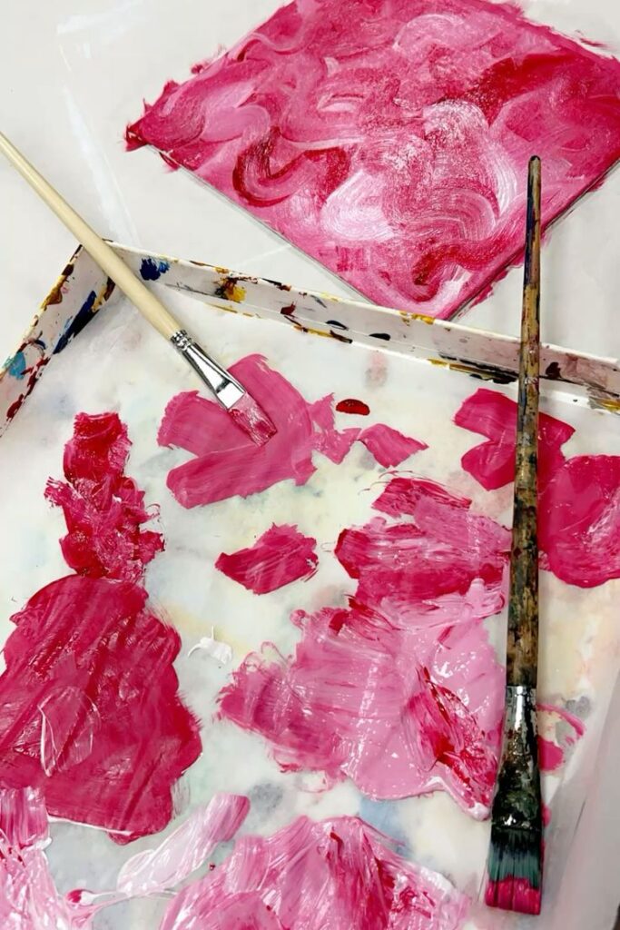 Pink paint and brushes on palette creating abstract art. Paint splatters and brushstrokes showcase creativity. Pink drawings