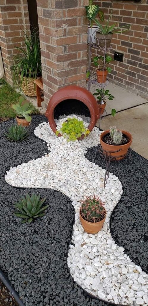 Creative garden landscaping with succulents, cacti, and decorative stones around a terracotta pot feature.