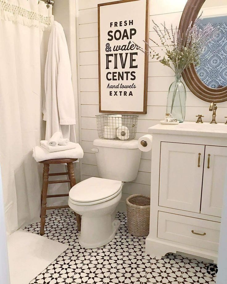 Charming farmhouse-style bathroom with a vintage sign, white vanity, and patterned floor tiles. Cozy and inviting decor.
