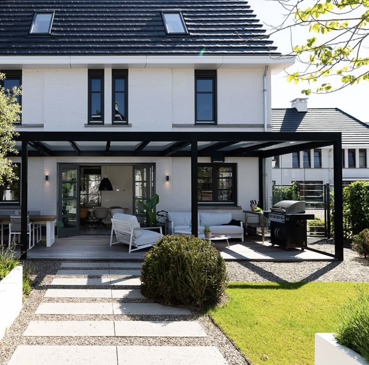 _ Modern house with glass-walled patio, outdoor seating, and grill, showcasing a stylish backyard retreat. | Sky Rye Design Modern house with glass-walled patio, outdoor seating, and grill, showcasing a stylish backyard retreat.