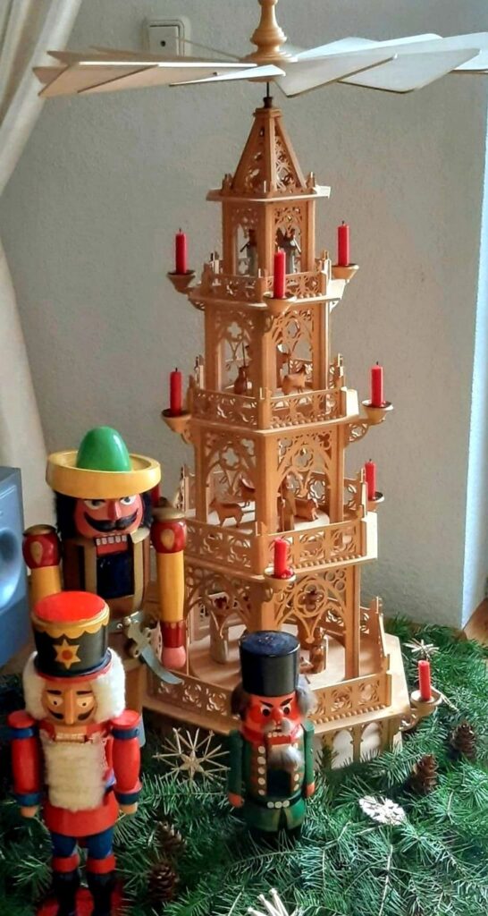 _ Wooden Christmas pyramid and colorful nutcrackers on a festive green display with candles and ornaments. | Sky Rye Design Wooden Christmas pyramid and colorful nutcrackers on a festive green display with candles and ornaments. German wooden