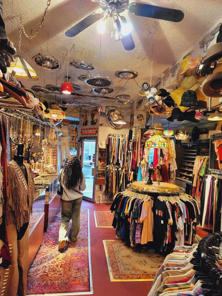 Vintage clothing store interior with racks of colorful clothes, unique decor, and a person walking out the door.