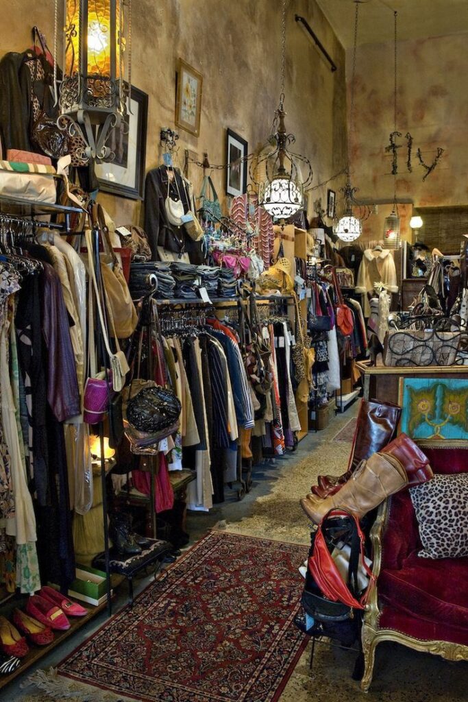 Vintage clothing store interior with racks of eclectic fashion, bags, and accessories in a cozy, rustic setting.